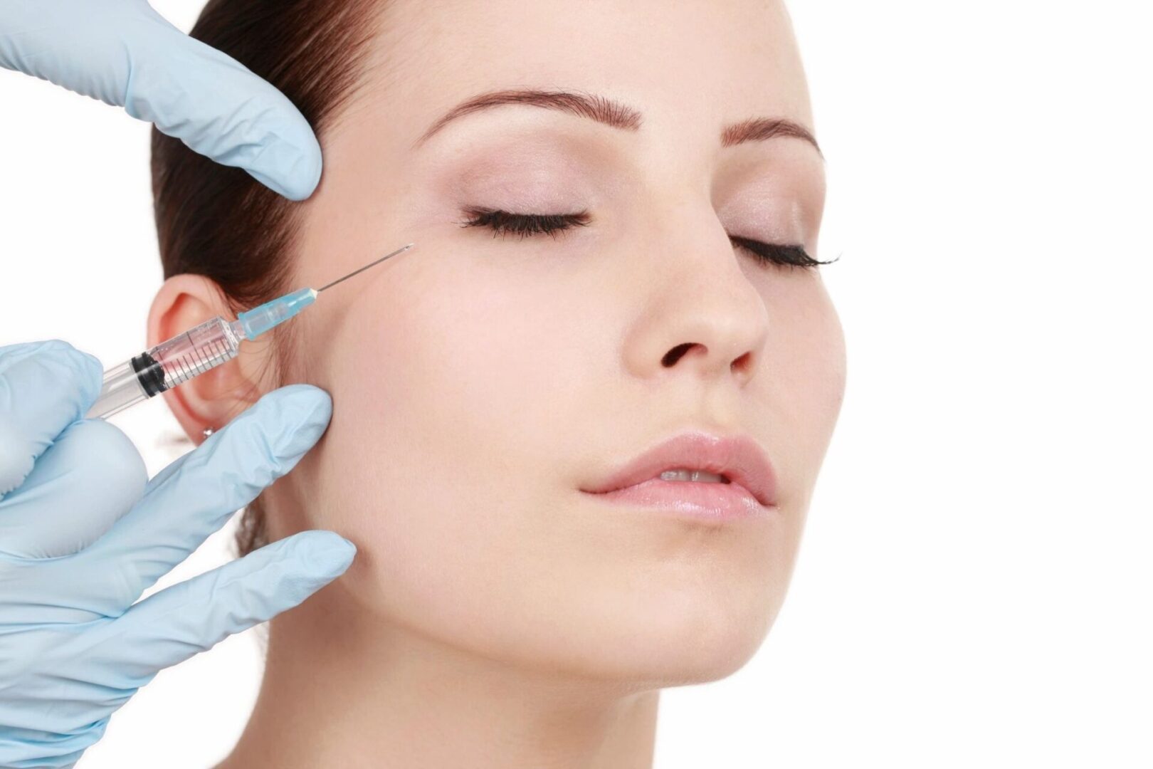 A woman getting her face waxed by two hands.