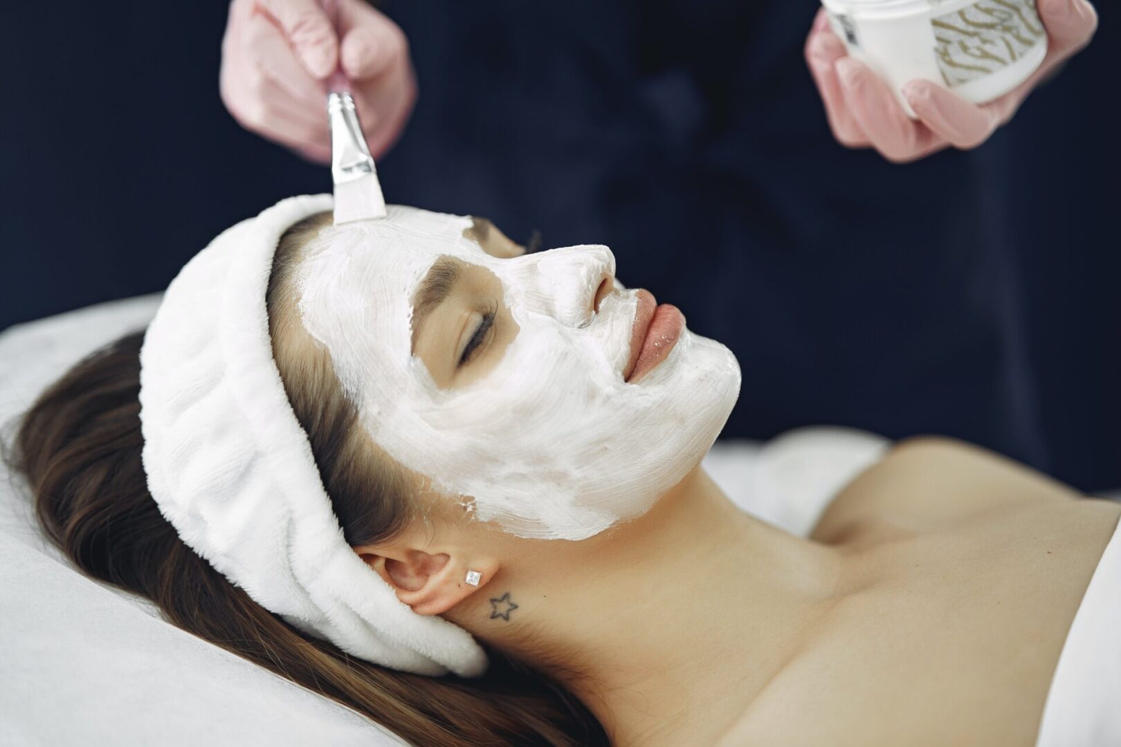 A woman getting her face painted with white clay.