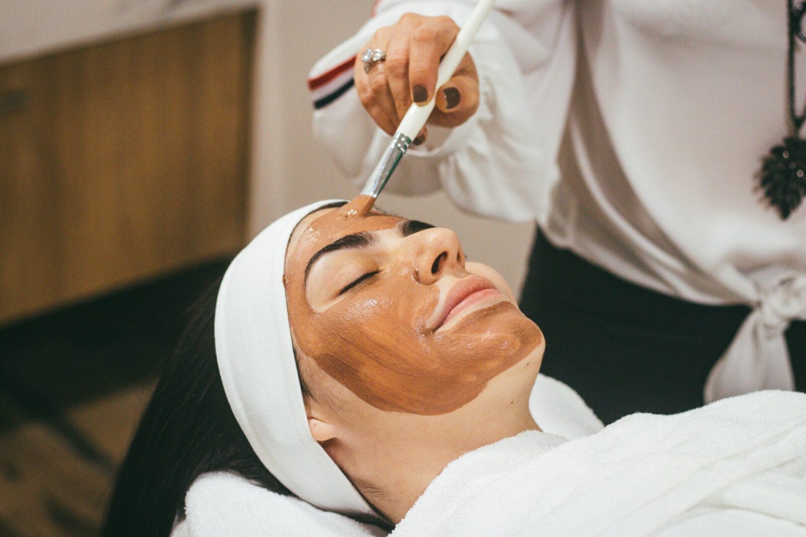 A woman getting her face painted with a brush.